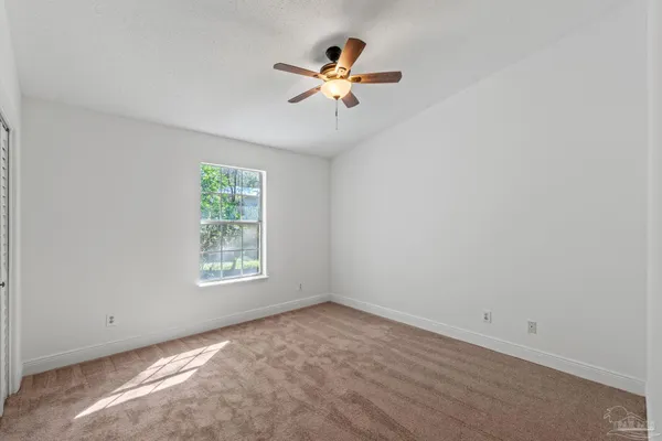 an empty room with a window and a fan
