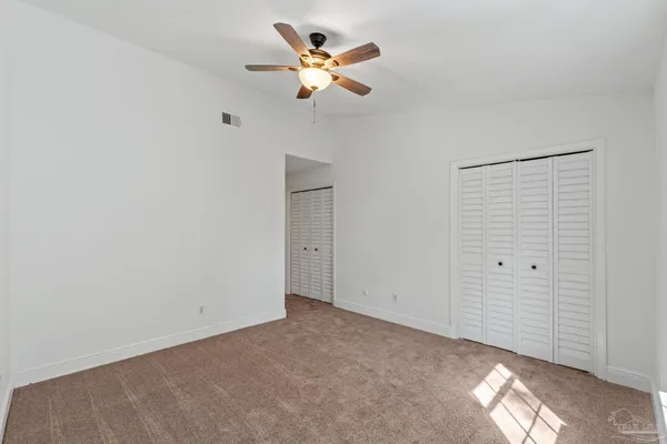 an empty room with closet and a ceiling fan
