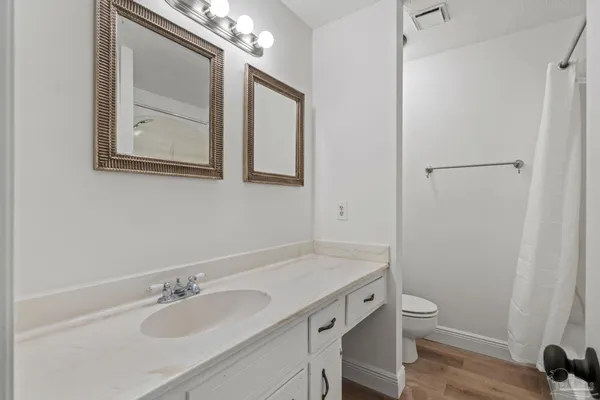 a bathroom with a granite countertop sink toilet and mirror