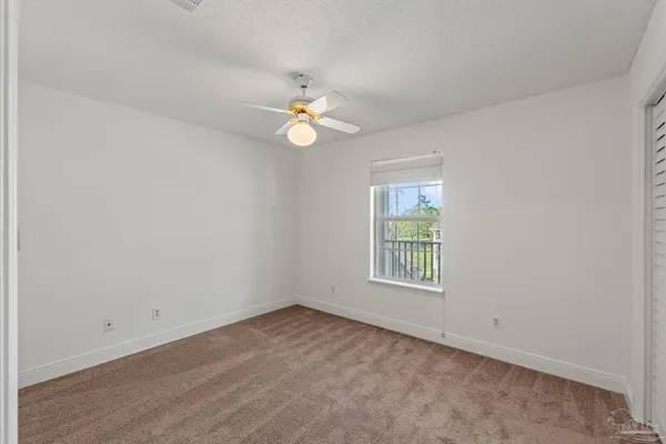 an empty room with a window and ceiling fan