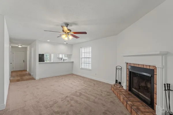 a view of an empty room with kitchen and fireplace