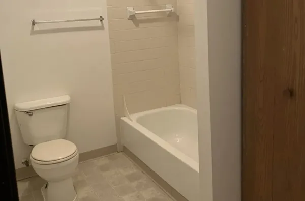 a white toilet sitting next to a bath tub