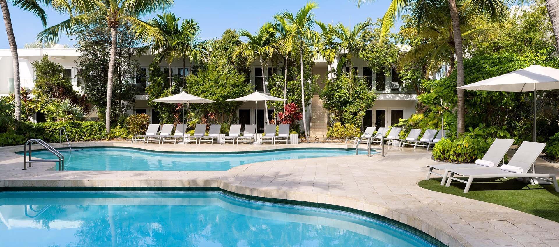 1401 Simonton Street, Unit 11 Key West, FL 33040 - Photo 13 of 17 a view of a swimming pool with lawn chairs under an umbrella