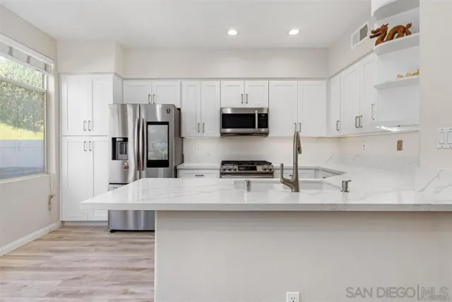 a large kitchen with stainless steel appliances a sink a stove a microwave a refrigerator and cabinets