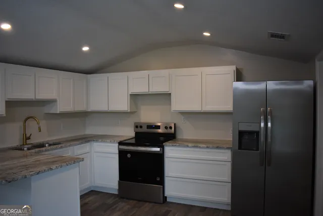 a kitchen with stainless steel appliances granite countertop white cabinets and a stove