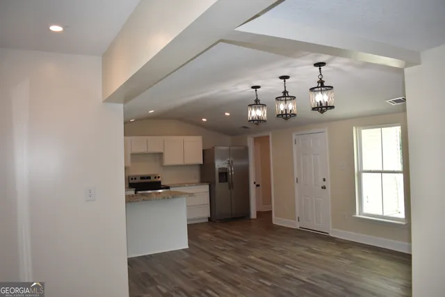 a kitchen with a refrigerator chandelier and wooden floor