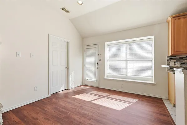 a view of an empty room with a window and wooden floor