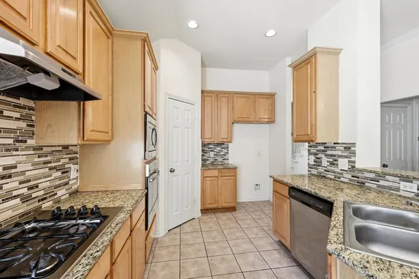 a kitchen with stainless steel appliances granite countertop a stove a sink and a refrigerator