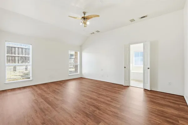 an empty room with wooden floor chandelier fan and windows