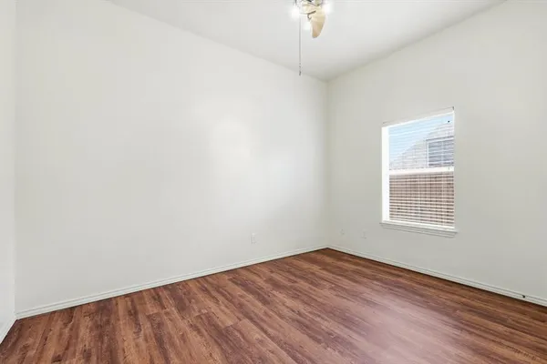 an empty room with wooden floor chandelier fan and windows