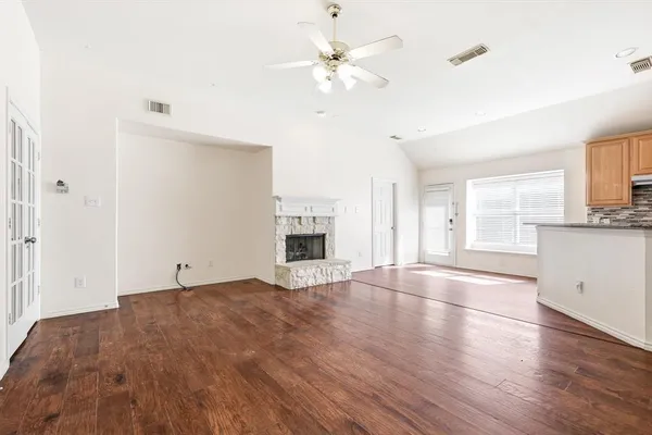 a view of an empty room with window and wooden floor