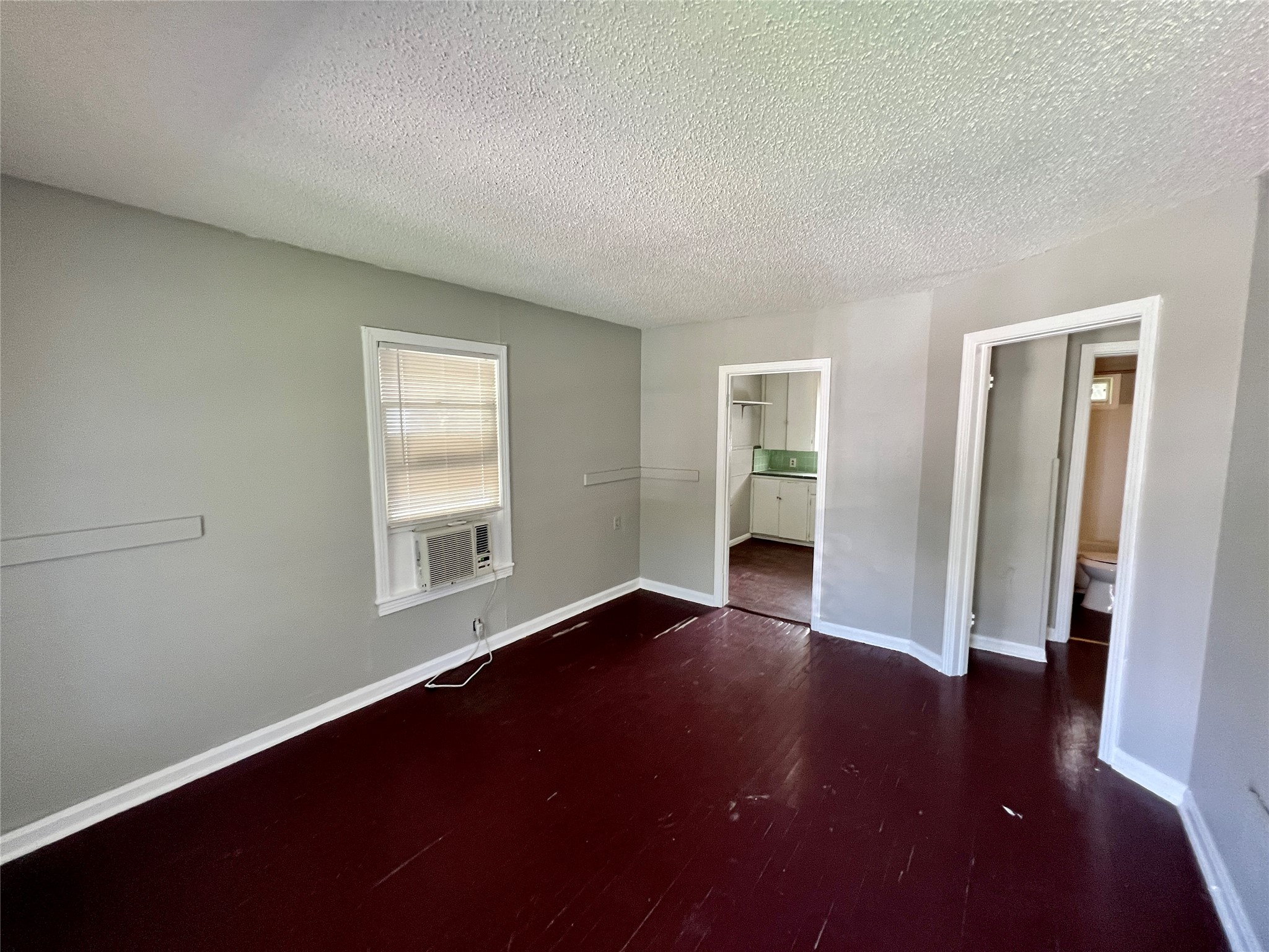 5409 Link Avenue Austin, TX 78751 - Photo 3 of 10 Unfurnished bedroom with a textured ceiling, dark wood-style floors, cooling unit, and ensuite bathroom