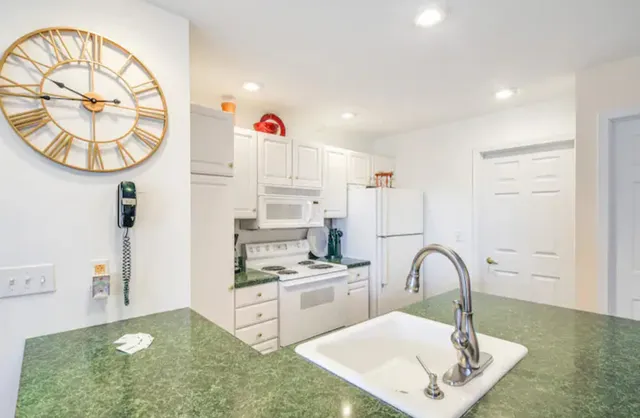 a kitchen with white cabinets a sink a stove and a dining table