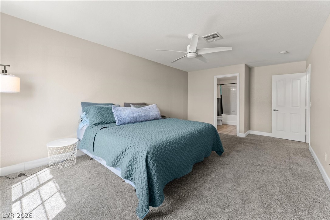 503 Rafkin Place Henderson, NV 89052 - Photo 9 of 18 A well-lit primary bedroom features soft carpeting and direct access to a private bathroom.