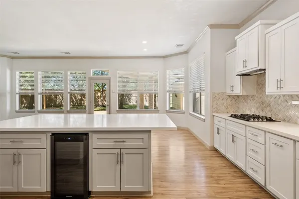 a large white kitchen with kitchen island a sink a center island and stainless steel appliances