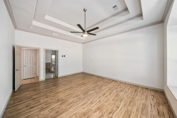 a view of an empty room with wooden floor window and chandelier fan