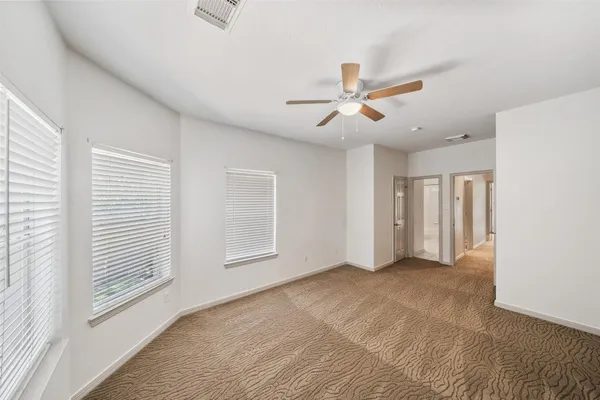 an empty room with chandelier fan and windows