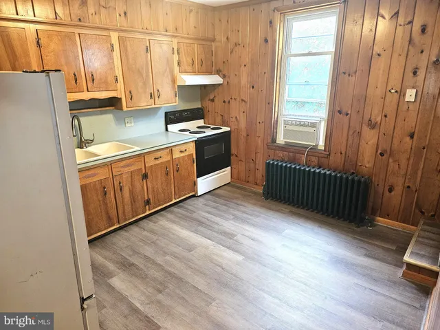 a kitchen with stainless steel appliances granite countertop a stove a sink and a refrigerator with wooden floor