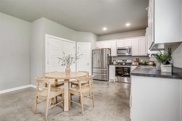 a kitchen with stainless steel appliances kitchen island granite countertop a table and chairs in it