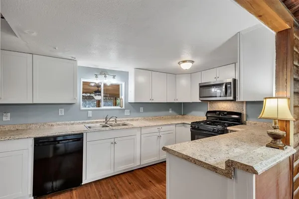 a kitchen with stainless steel appliances granite countertop a sink stove microwave and refrigerator
