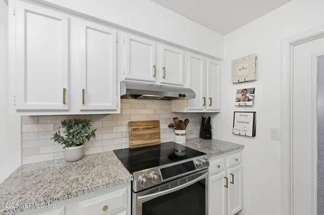 a kitchen with granite countertop white cabinets and white appliances