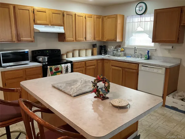 a kitchen with stainless steel appliances kitchen island granite countertop a table chairs in it and white cabinets