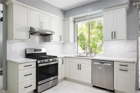 a kitchen with white cabinets and appliances