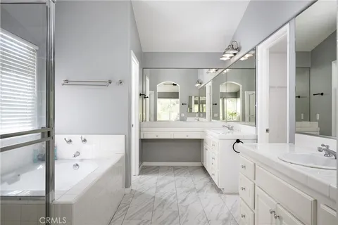 a spacious bathroom with a tub sink and mirror