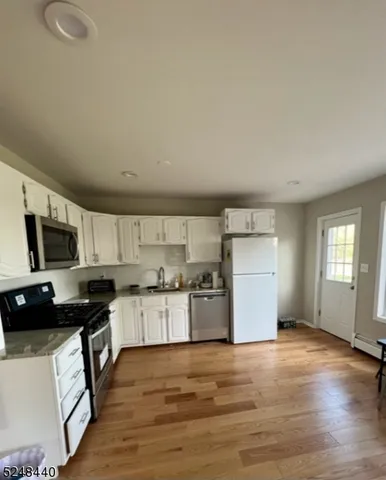 a kitchen with granite countertop a refrigerator stove top oven and sink