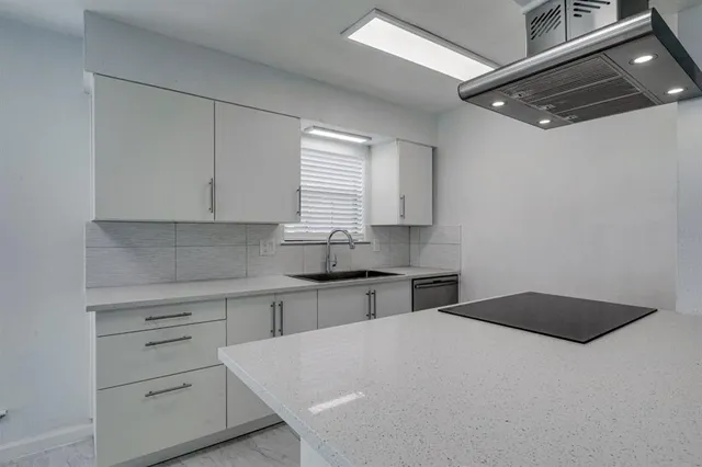 a kitchen with a white cabinets appliances and a window