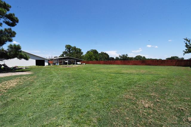107903 South 4570 Road Sallisaw, OK 74955 - Photo 35 of 35 Expansive grassy lot featuring a metal-sided outbuilding, a covered open-air structure, and a perimeter fence