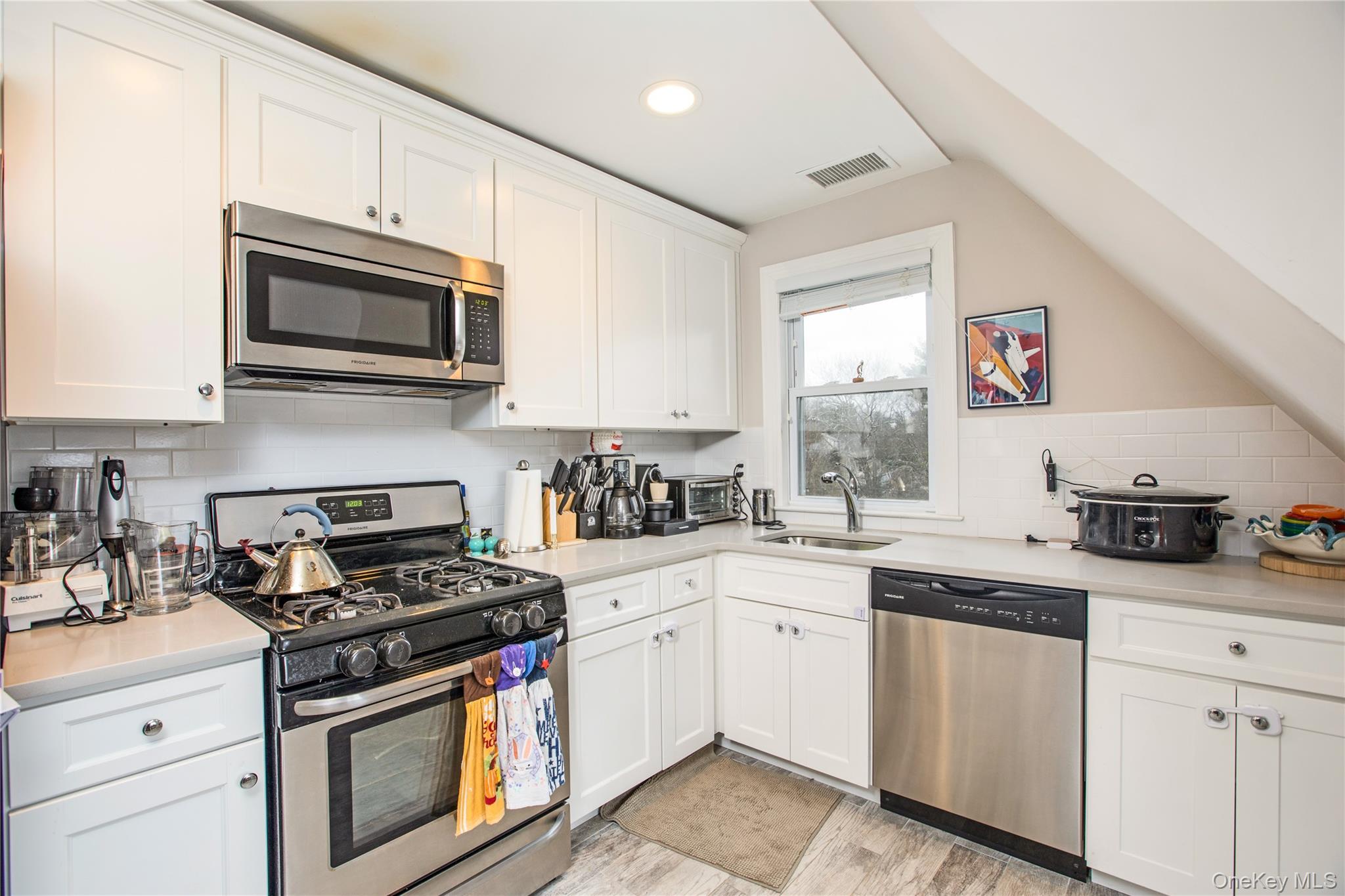 199 Purchase Street, Unit 2 Rye, NY 10580 - Photo 8 of 14 a kitchen with stainless steel appliances granite countertop white cabinets a sink a stove a microwave and wooden floors