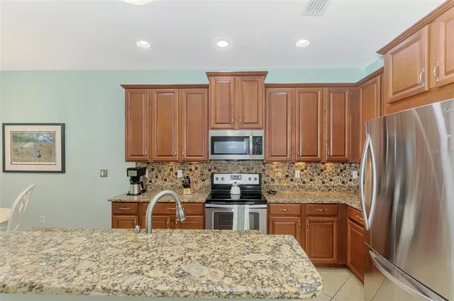 a kitchen with stainless steel appliances granite countertop a stove top oven a sink a dining table and chairs with wooden floor