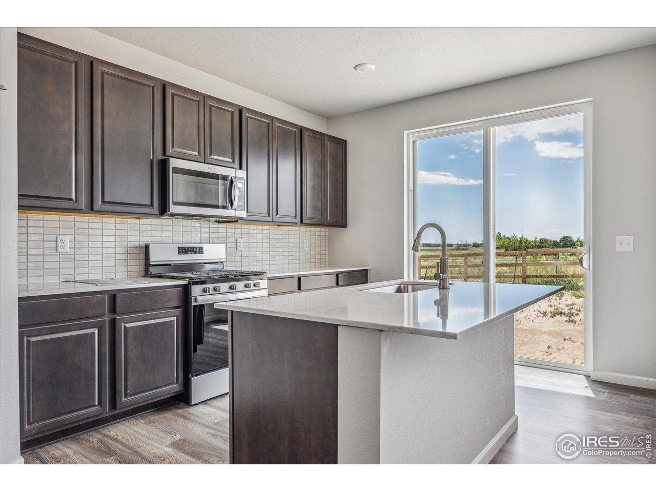 882 Mesic Lane Windsor, CO 80550 - Photo 11 of 26 a kitchen with stainless steel appliances granite countertop a sink stove and microwave