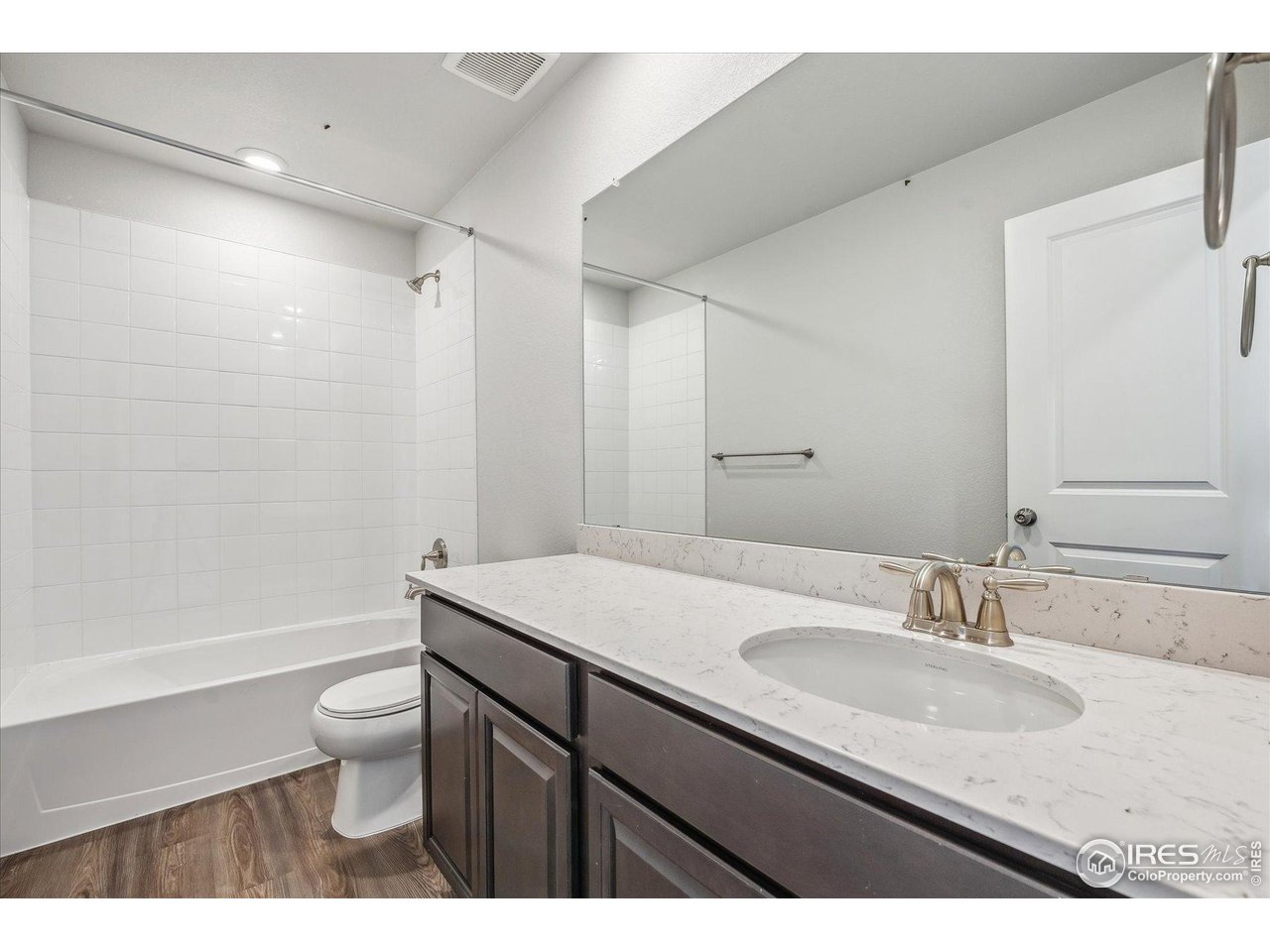 882 Mesic Lane Windsor, CO 80550 - Photo 16 of 26 a bathroom with a granite countertop sink a toilet a mirror and bathtub