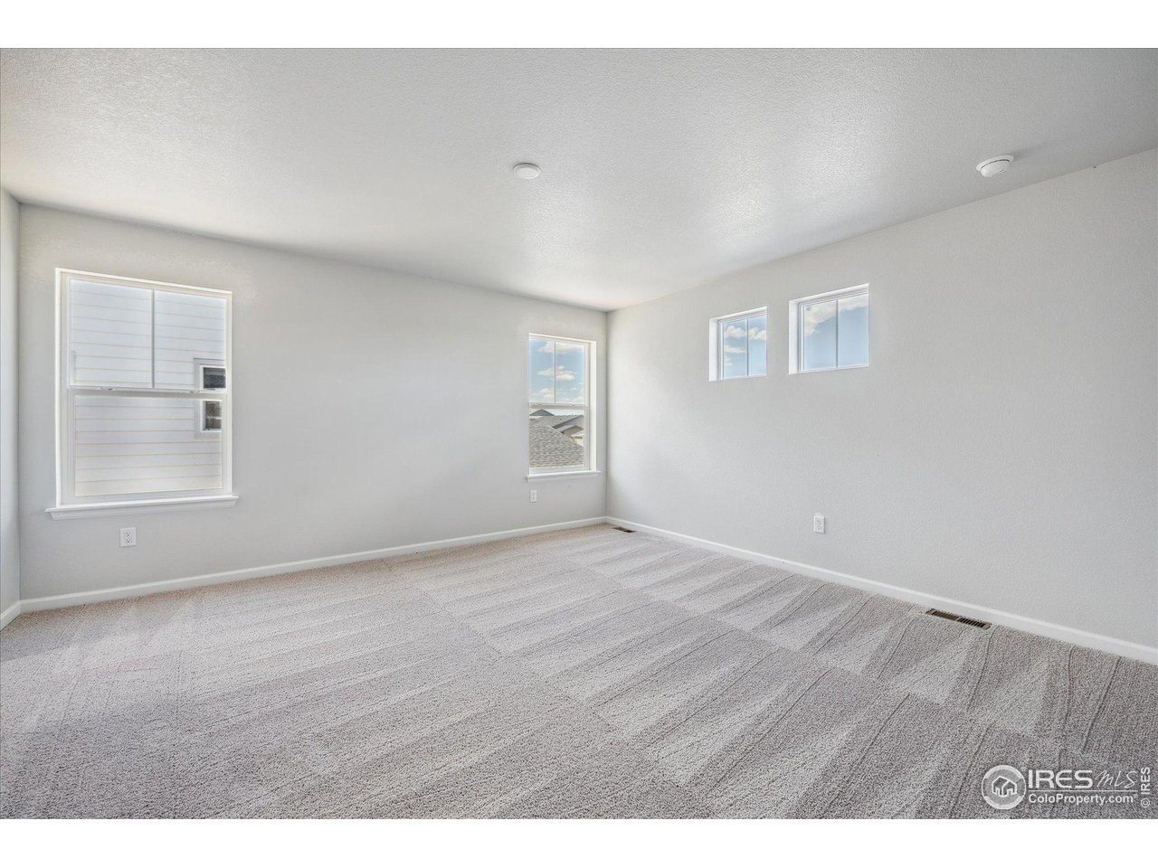 882 Mesic Lane Windsor, CO 80550 - Photo 19 of 26 an empty room with wooden floor and windows