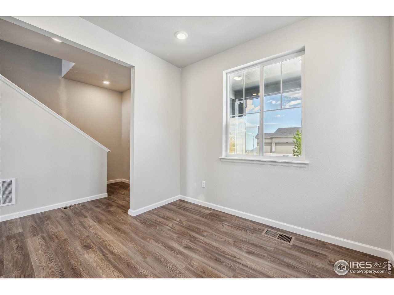 882 Mesic Lane Windsor, CO 80550 - Photo 2 of 26 an empty room with wooden floor and windows