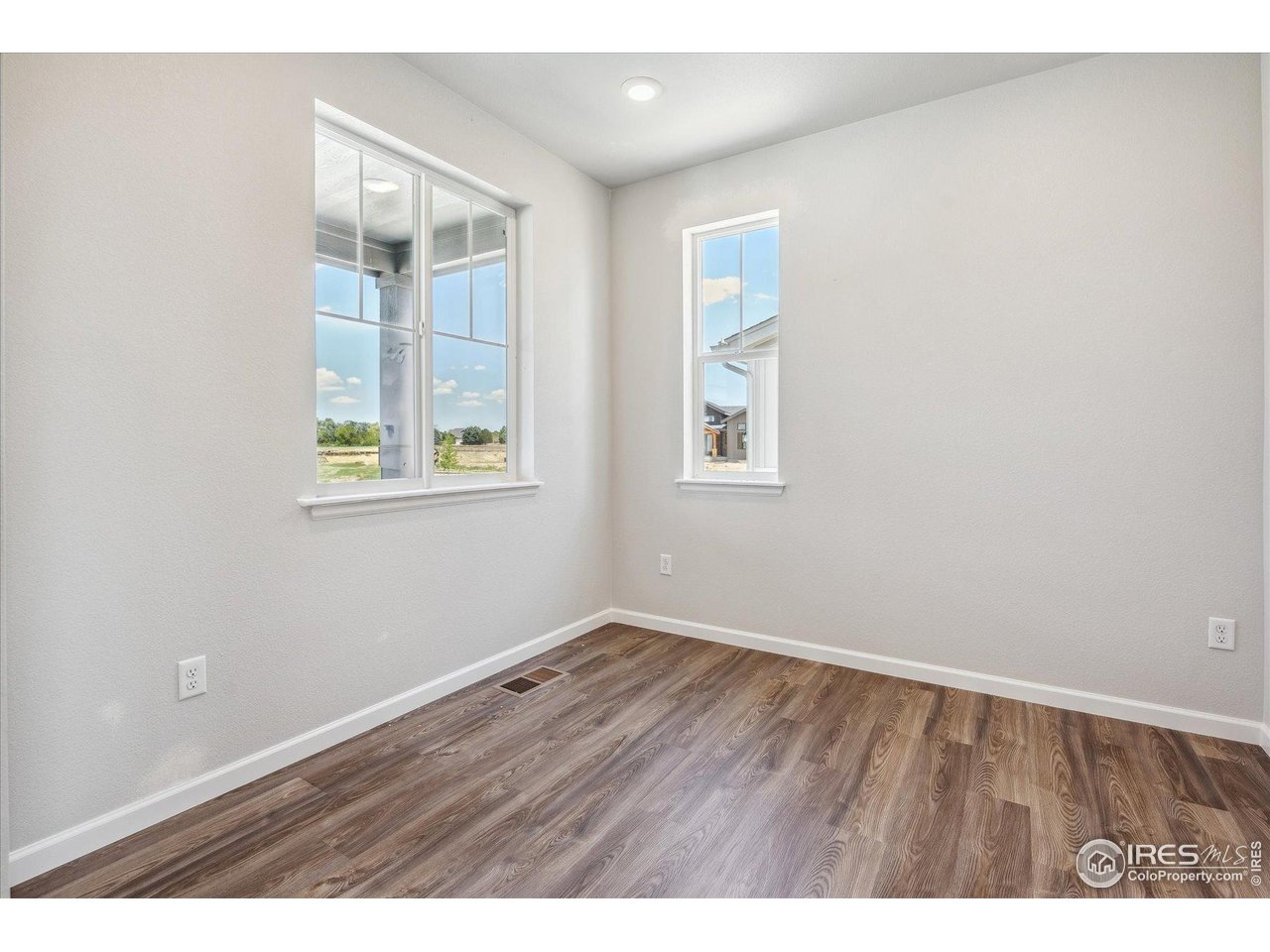 882 Mesic Lane Windsor, CO 80550 - Photo 4 of 26 an empty room with wooden floor and windows