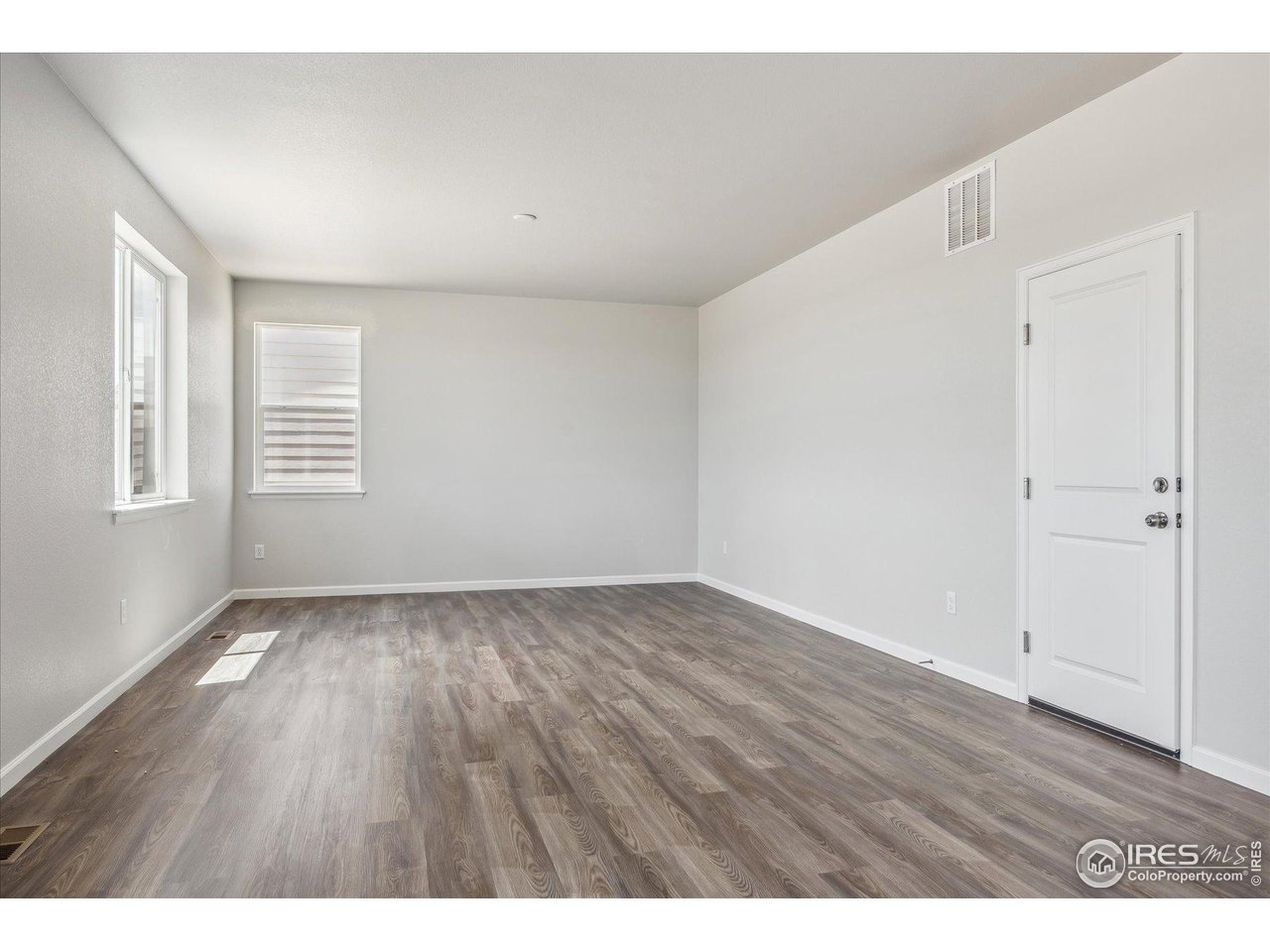 882 Mesic Lane Windsor, CO 80550 - Photo 6 of 26 a view of an empty room with wooden floor and a window