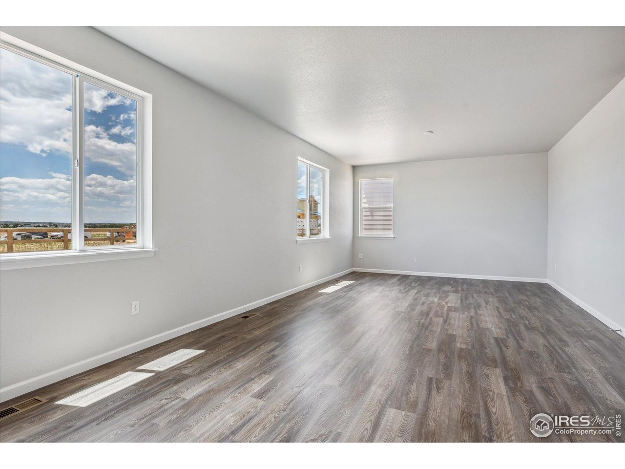 882 Mesic Lane Windsor, CO 80550 - Photo 7 of 26 a view of an empty room with wooden floor and a window