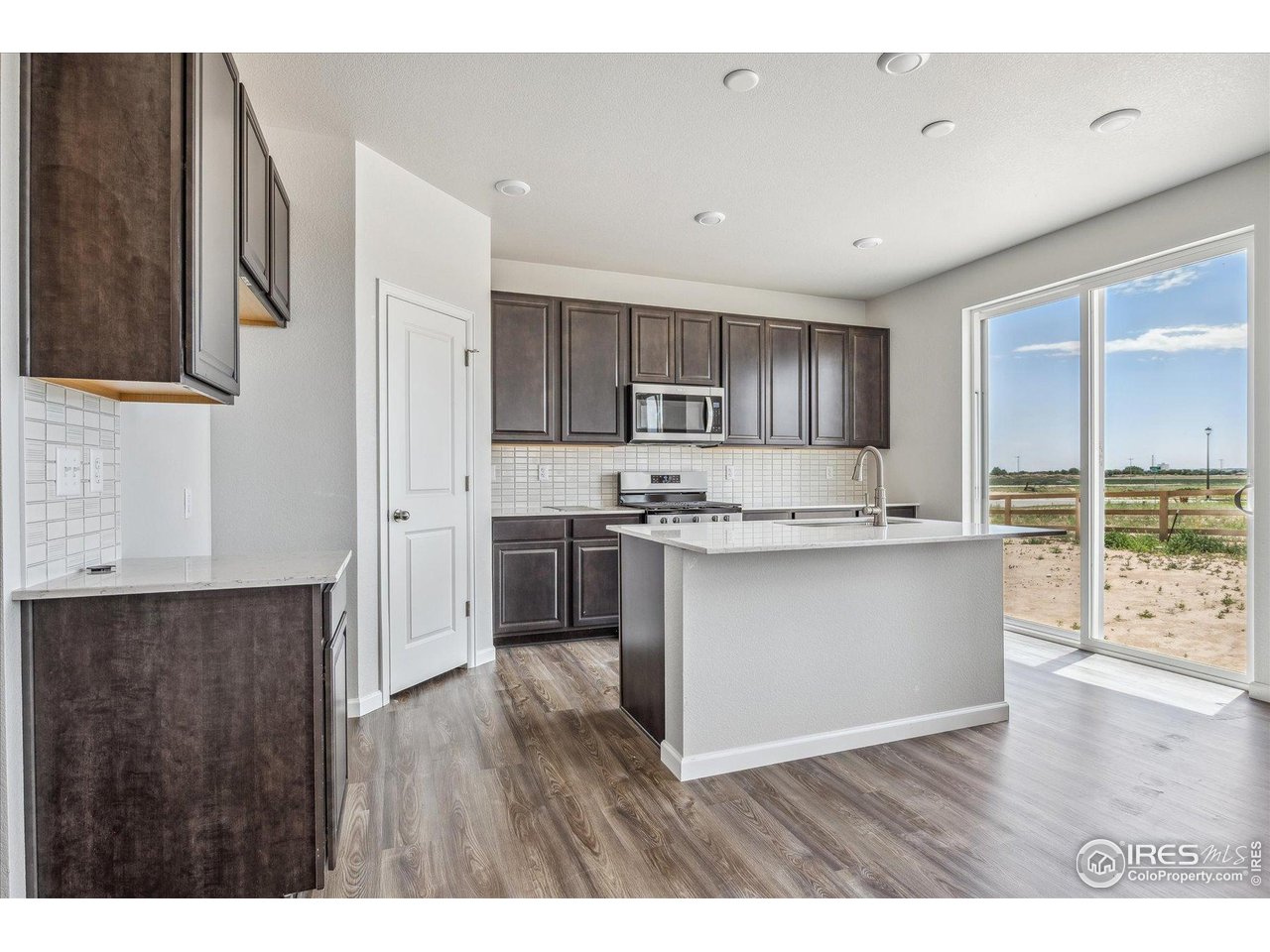 882 Mesic Lane Windsor, CO 80550 - Photo 10 of 26 a kitchen with stainless steel appliances granite countertop a refrigerator a sink dishwasher a stove with wooden floor and cabinets