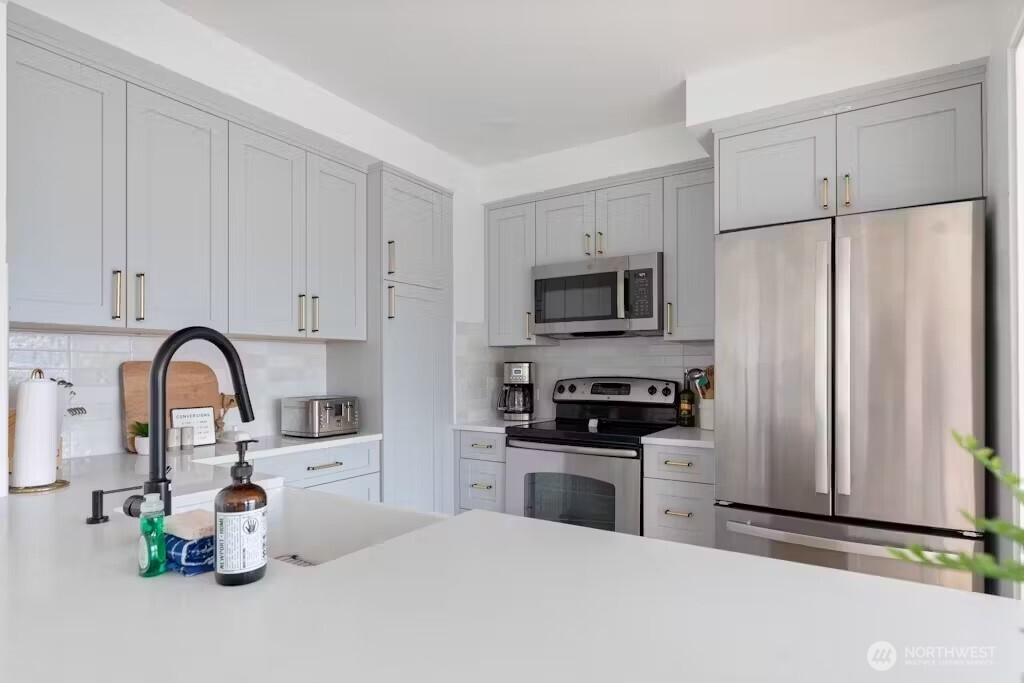 6192 Kohlwes Road Clinton, WA 98236 - Photo 7 of 12 a kitchen with white cabinets and stainless steel appliances