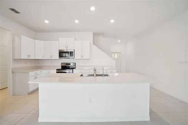 a kitchen with kitchen island sink stove and cabinets
