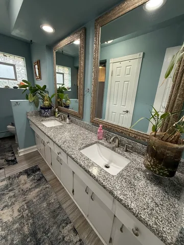 a bathroom with a granite countertop double vanity and a mirror