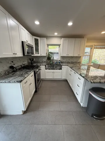 a kitchen with stainless steel appliances granite countertop a stove a sink and a microwave