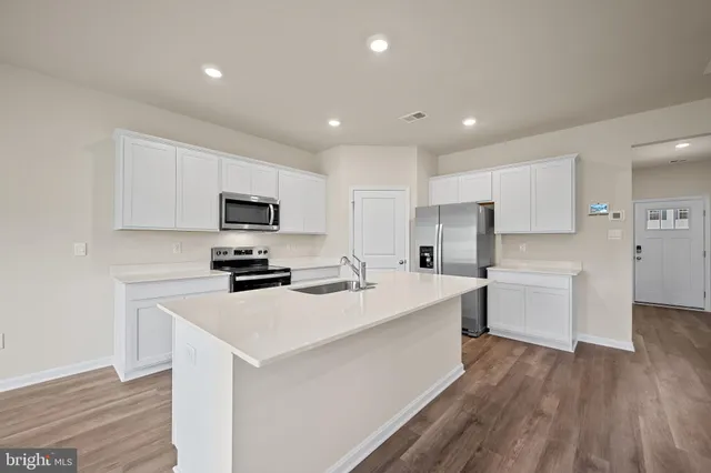 a kitchen with a sink a counter top space stainless steel appliances and cabinets