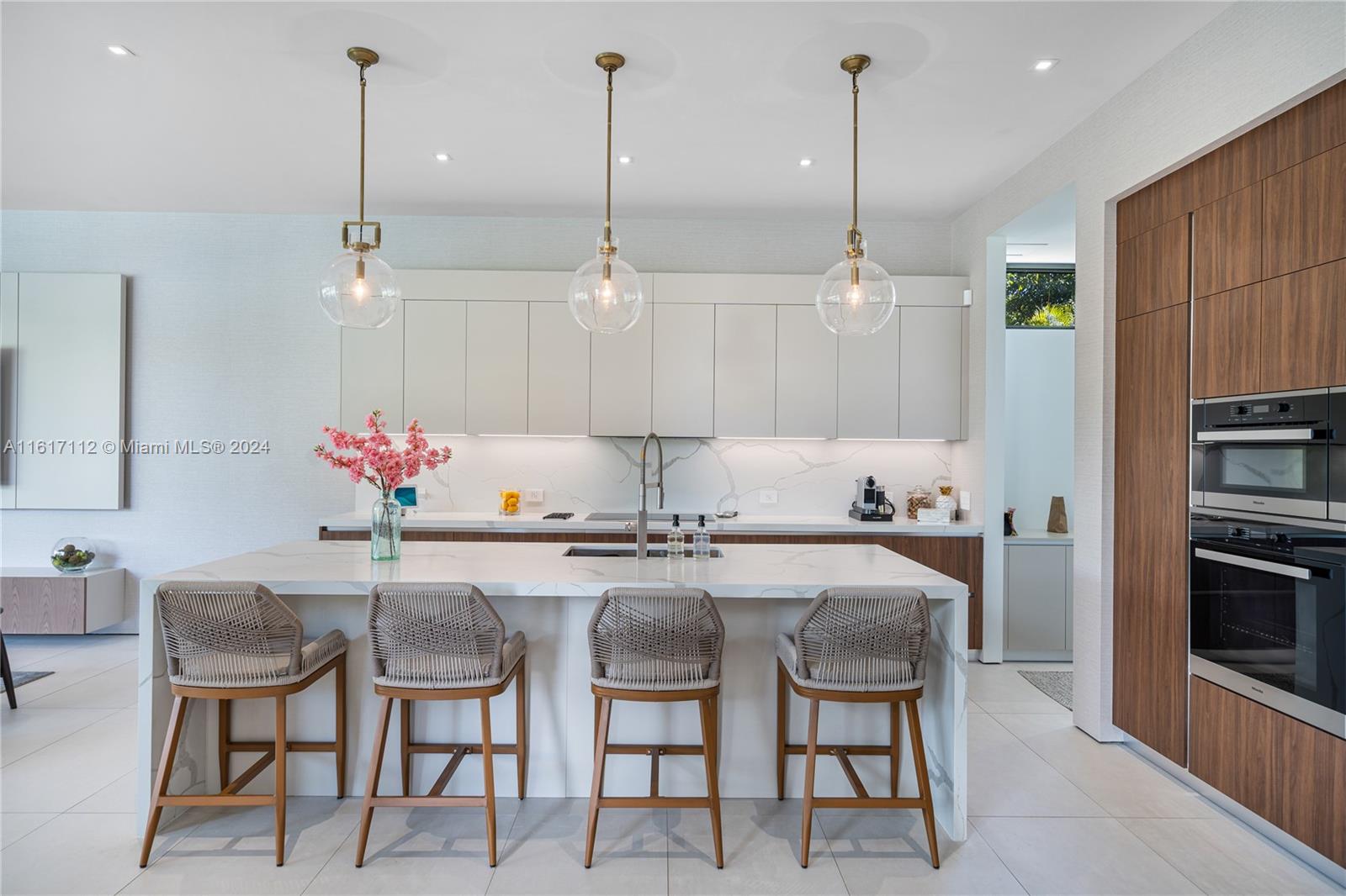 7825 Southwest 128th Street Pinecrest, FL 33156 - Photo 10 of 40 a kitchen with kitchen island granite countertop a dining table chairs and white cabinets