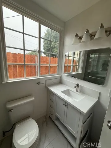 a bathroom with a toilet sink a window and mirror