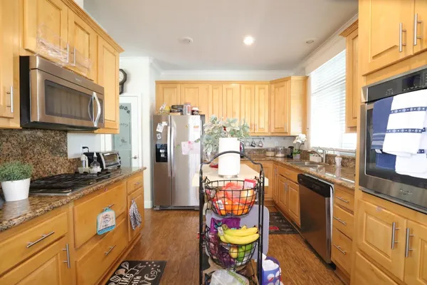 a kitchen with stainless steel appliances kitchen island granite countertop a refrigerator a sink a stove and blue cabinets