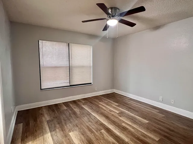 an empty room with a window and a ceiling fan